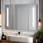 A modern bathroom features the Signature Royale 36 Inch x 36 Inch LED Lighted Mirror Medicine Cabinet above a white basin sink, with white subway tile walls and Edison bulb lights on each side. Toiletries sit neatly beside the sink.