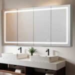 A modern bathroom features the Signature Royale 72" x 36" LED Lighted Mirror Glass Medicine Cabinet above two white rectangular sinks with black faucets, a small green plant between them, and towels stored on shelves below.