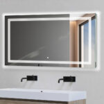 A Soho 60 Inch x 30 Inch LED Lighted Bathroom Mirror hangs above a modern white sink with two black wall-mounted faucets; the backlit mirror reflects a window and part of a gray wall.