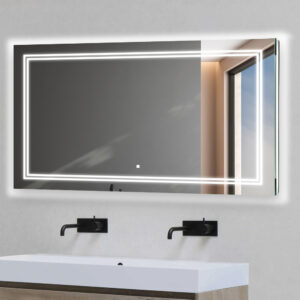 A Soho 60 Inch x 30 Inch LED Lighted Bathroom Mirror hangs above a modern white sink with two black wall-mounted faucets; the backlit mirror reflects a window and part of a gray wall.