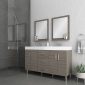 Modern bathroom with gray tile, a glass-enclosed shower, a double-sink vanity with wood cabinets, two rectangular mirrors, silver fixtures, and a potted succulent on the floor. Towels hang on a ring by the vanity.