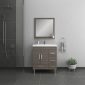 A modern bathroom with a dark grey tiled shower on the left, a wood vanity with a white sink and silver handles, a square mirror above, a towel ring with a towel, and a potted succulent on the right.