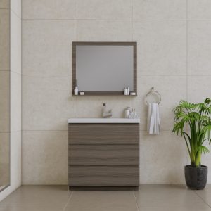 A modern bathroom with beige tiled walls, a wooden vanity with a white countertop, a rectangular mirror, toiletries on a shelf, a towel on a ring, and a potted green plant on the floor.