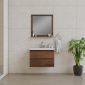 Minimalist bathroom with beige tiled walls, a wooden floating vanity with a white sink, a square mirror above, toiletries on the sink, a towel hanging on a ring, and a potted green plant on the floor.