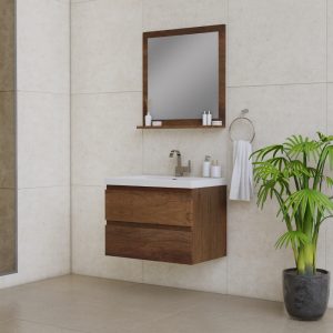 A modern bathroom with a wooden floating vanity, white sink, and matching mirror. A hand towel hangs on the wall, and a potted green plant sits on the floor beside the vanity. The walls and floor are beige tiles.