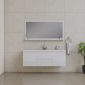 Minimalist bathroom with beige tiled walls and floors, a white floating vanity with a sink, a large rectangular mirror, and a small green plant in the corner. A towel hangs on a ring beside the vanity.