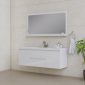 Modern bathroom with beige tiled walls, a large rectangular mirror above a white floating vanity, a sink with a single faucet, toiletries, a hand towel on a ring, and a green potted plant in the corner.