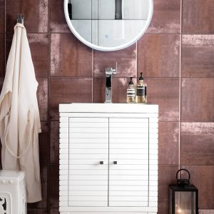 The tranquil bathroom scene includes a Linden 24 inch Bathroom Vanity in Glossy White with a double-door cabinet. A glowing round mirror hangs above, while the countertop holds soap and lotion dispensers. A robe is nearby, a lantern rests on the floor, and walls feature a copper-like finish.