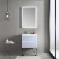 A minimalist bathroom features a sleek white Jena 24-inch Wall Mount Vanity with LED Lights and an illuminated mirror. A glass dispenser and towels rest on a round glass table, under a modern pendant light. A floor-to-ceiling window on the right enhances the clean, contemporary look with neutral tones.