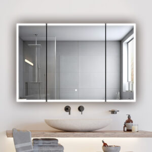 A modern bathroom features a round stone sink on a wooden counter, folded towels, and toiletries. An Edge Royal 48 Inch LED Lighted Mirror 3 Door Medicine Cabinet serves as a large mirror, reflecting the shower with gray tiles and a window.