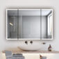 A modern bathroom features a round stone sink on a wooden counter, folded towels, and toiletries. An Edge Royal 48 Inch LED Lighted Mirror 3 Door Medicine Cabinet serves as a large mirror, reflecting the shower with gray tiles and a window.