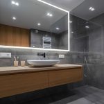 Modern bathroom with a floating wooden vanity, round sink, Edge 96 Inch LED Lighted Bathroom Mirror, gray tiled walls and floor, glass-enclosed shower, and minimal accessories on the counter.