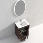 The Hanover 24 inch Bathroom Vanity With Sink showcases open cabinet doors and a drawer with toiletries. Above it, a round illuminated mirror on a light gray wall adds style to the bathroom.