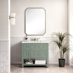 A modern bathroom features a Breckenridge 36" Bathroom Vanity in Smokey Celadon with a White Zeus Top, brass fixtures, a geometric mirror, half-tiled walls accented by a double wall sconce, and a potted plant on the right.