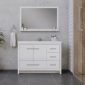 Modern bathroom with a large rectangular mirror above a white vanity with drawers and a sink. Gray tile floor, towel ring with white towel, and concrete and wood-paneled walls are visible. Minimalist décor.