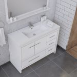 Modern white bathroom vanity with a rectangular sink, silver faucet, and drawers, set against a gray and white tiled wall, with towels and toiletries neatly arranged on the countertop.