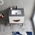 The Burano 30 inch Beige Freestanding Bathroom Vanity features a gray countertop, white rectangular sink, black faucet, and two white drawers on wooden legs. Nearby are a toothbrush holder, towel, and a blue and white rug on the floor.
