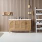 A modern bathroom includes the Nara 60 inch Freestanding Bathroom Vanity in Pecan Oak with woven cane cabinet doors, a wooden slat wall, gold pendant lights, a white shelving unit for toiletries, and a small wooden wall shelf.