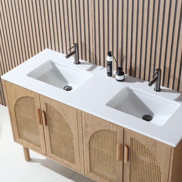The Nara 60 inch Freestanding Bathroom Vanity in Pecan Oak features dual white sinks, sleek faucets, light wood cabinets with rattan panels, and a countertop with toiletries, all set before a vertical wooden slat wall.