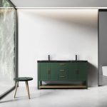 A modern bathroom features the Winchester 60 inch Forest Green Freestanding Bathroom Vanity with a black countertop and dual sinks. A wooden stool sits by a large window showcasing lush greenery, while a toilet is seen in the adjacent room against white walls.