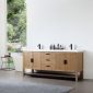 A modern bathroom showcases the Winchester 72-inch Pecan Oak Freestanding Vanity with a white countertop, accented by sleek black faucets and handles. Assorted toiletries are neatly placed on the vanity.