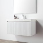 The Positano 36 inch Wall Mount Bathroom Vanity in Matte White With Sink features a modern floating design, textured front drawer, sleek white countertop with faucet, two small bottles, and is paired with a large frameless mirror for a clean look.