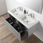 The Positano 48 inch Double Wall Mount Bathroom Vanity in Light Gray features dual sinks, chrome faucets, a large wall mirror, and open drawers for toiletries, set against a light wall and wood flooring for a sleek modern look.