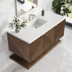 Modern bathroom vanity with a white countertop, rectangular sink, brass faucet, wood cabinets with geometric patterns, a vase of white flowers, soap dispenser, large mirror, and marble wall and floor tiles.