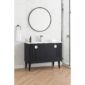The Venezian 48 inch Bathroom Vanity with a black cabinet, white countertop, and chrome faucet sits below a round mirror on a white marble wall. A towel ring with a white towel and glass shower enclosure are also visible.
