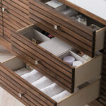 The Linear 72 inch Single Bathroom Vanity Cabinet features three open drawers for towels, toiletries, and essentials. Its slatted wood design pairs perfectly with a light wood floor, creating a modern bathroom aesthetic.