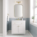 A modern bathroom with the Chicago 30 inch Bathroom Vanity Cabinet, gold faucet and handles, a rectangular gold-trimmed mirror, a globe light above, blue subway tile wainscoting, and a window ledge with a small plant.