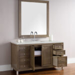 The Chicago 60 inch Single Bathroom Vanity Cabinet includes a wooden-framed mirror, spacious design with multiple drawers and cabinet, a sink with dual faucets, and a countertop adorned with a toilet paper roll and jar.
