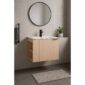 This modern bathroom showcases the Elmridge 24 Wall Mounted Bathroom Vanity with a sink, a black faucet, and a round mirror. A potted plant sits on the ledge, complemented by a dark towel on a black rack and a beige mat on dark tiles, highlighting its minimalist style.