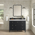 An elegant bathroom showcases the Lorelai 48 Single Vanity Cabinet with brass knobs, a white countertop, and a decorative mirror. Pendant lights hang overhead, complemented by light-colored tile walls and wood flooring. White towels on gold rings complete the look.