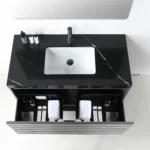 The Matera 36 Inch Wall Mount Bathroom Vanity With Countertop showcases black marble, a white rectangular sink, a sleek faucet, and three bottles on top, with an open drawer below for towels and organized toiletries.