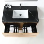The Matera 36 Inch Wall Mount Bathroom Vanity With Countertop includes a black marble top, white rectangular sink, and wooden drawer perfect for toiletries and towels, while bottles are neatly arranged on the surface.
