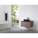 Minimalist bathroom with the Ocala 36 Inch Wall Mount Bathroom Vanity With Vessel Sink, black faucet, towel ladder, white tub, decorative giraffe figures, gray rug, and a large window overlooking greenery.
