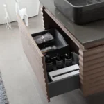 The Ocala 48 Inch Wall Mount Bathroom Vanity With Vessel Sink showcases a dark countertop, open drawer with towels and bottles, and is accented by a textured gray rug plus two white giraffe figurines.
