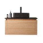 The Ocala 36 Inch Wall Mount Bathroom Vanity With Vessel Sink has modern light wood, a textured front panel, black countertop, rectangular black vessel sink, tall black faucet, plus a gray soap dispenser and small containers on the left.