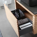 The Ocala 48 Inch Wall Mount Bathroom Vanity With Vessel Sink includes light wood drawers with matte gray dividers for organized storage, and is paired with a matching gray countertop and rug for a sleek, modern look.