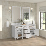 The Lorelai 60 inch Double Bathroom Vanity includes dual sinks, open storage for baskets and towels, and is paired with two mirrors and wall lights. Large windows brighten the area with natural light.