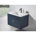 The Barcelona 30 Inch Wall Mount Bathroom Vanity features a navy blue fluted front, gold handle, white countertop, rectangular sink, black faucet, and soap dispenser, set against a white wall and gray floor.