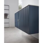 A modern Barcelona 42 Inch Wall Mount Bathroom Vanity in blue with vertical grooves and a gold handle, set against a light gray tiled floor and white wall, with towels on a black rack in the background.