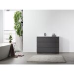 A modern minimalist bathroom features a Rothenburg 42 Inch Freestanding Bathroom Vanity, a light gray rug, a white freestanding tub, potted plants, and bright white walls illuminated by natural light.