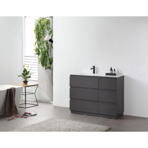 Modern bathroom with a Rothenburg 42 Inch Freestanding Bathroom Vanity, black faucet, small bottles, and light gray rug. A plant on a side table and a hanging green plant add greenery as sunlight streams through the window.