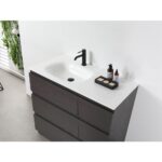 The Rothenburg 42 Inch Freestanding Bathroom Vanity has a white countertop, integrated sink, matte black faucet, soap dish with three soaps, two bottles, and a plant beside a white wall.