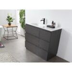 A modern bathroom showcases a Rothenburg 42 Inch Freestanding Bathroom Vanity with a dark wood finish, white countertop, and black faucet. Toiletries sit on the counter beside a small table with a potted plant and gray tile flooring.