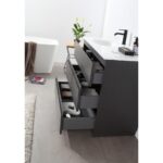Rothenburg 42 Inch Freestanding Bathroom Vanity with three drawers storing towels and toiletries stands by a white bathtub, a plant on the counter, and a brown towel nearby. A rug and scattered items cover the floor.
