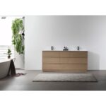 A modern bathroom features a Rothenburg 72 Inch Freestanding Vanity in light wood, gray floor tiles, a white rug, a bathtub with a towel draped over the side, and hanging green plants. The bright space showcases minimalist decor.