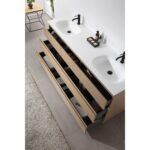 A modern bathroom featuring the Rothenburg 72 Inch Freestanding Vanity with dual sinks, black faucets, and light wood drawers storing towels and toiletries. A small plant stand and rug accent the nearby tiled floor.